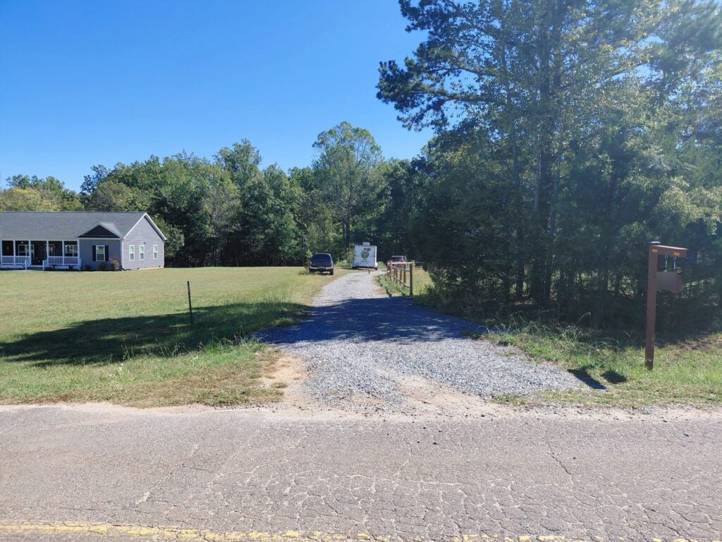 Long gravel driveway beside a split-rail fence before it was paved with asphalt